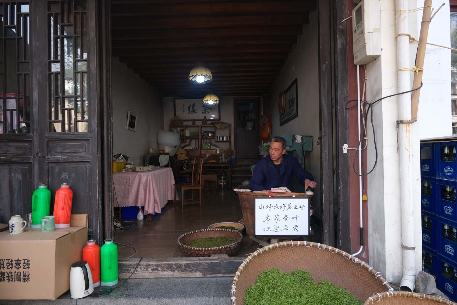 A villager dries freshly picked tea leaves outside his store in Meijiawu.